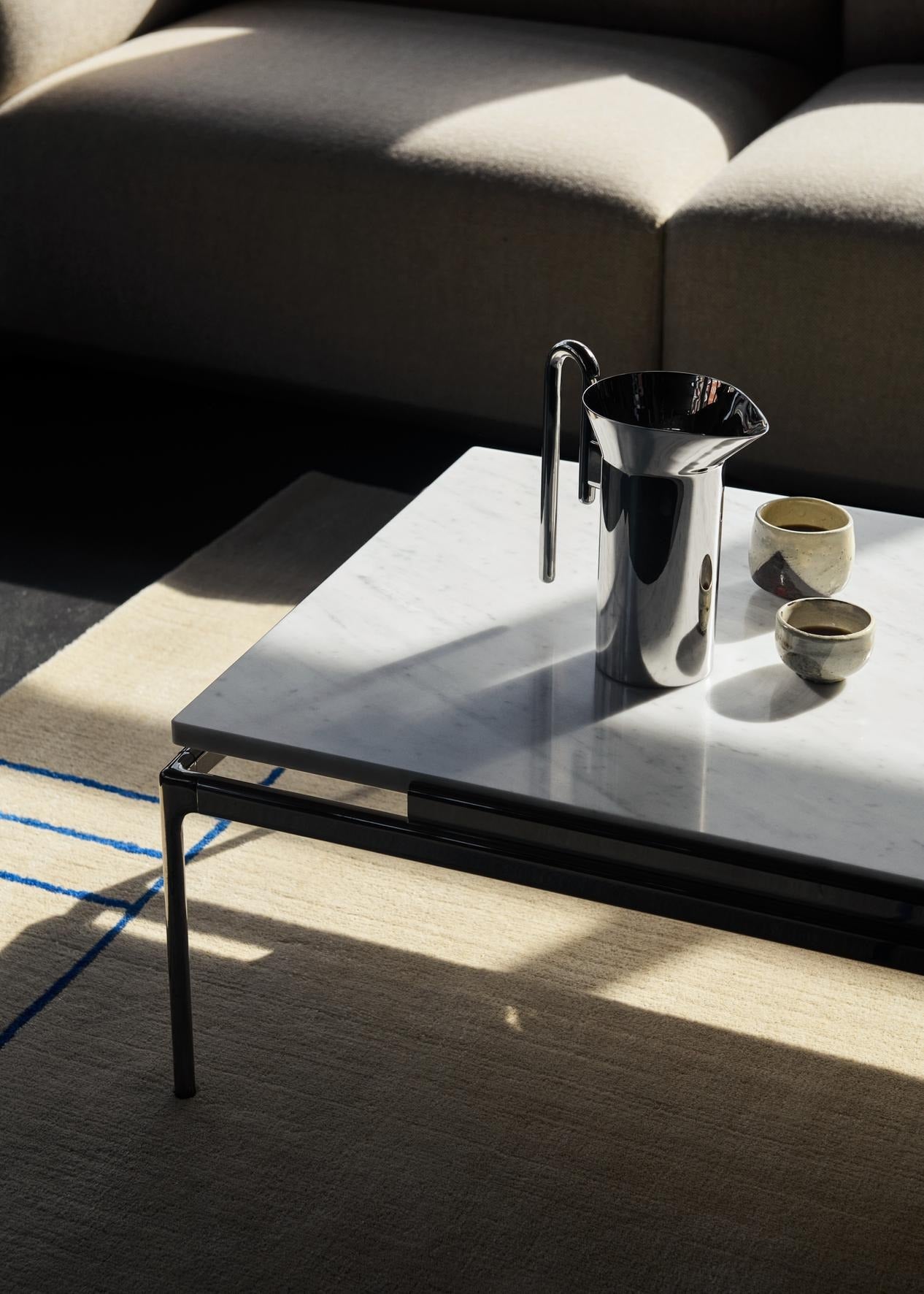 Mesa de centro &Tradition Sett LN12 con estructura de aluminio y sobre de cristal, diseñada por Luca Nichetto; Sett Coffee Table LN12 — ATD_Retail_2024_Sett LN12_Momento Jug JH38_Cruise AP12; Sett Coffee Table LN12 — ATD_Retail_2024_Sett LN12_detail_4; Sett Coffee Table LN12 — Sett LN12_Smoked cast glass w. Dark Chrome; Sett Coffee Table LN12 — ATD_Retail_2024_Sett LN12_Collect Glass SC61_The Moor AP7