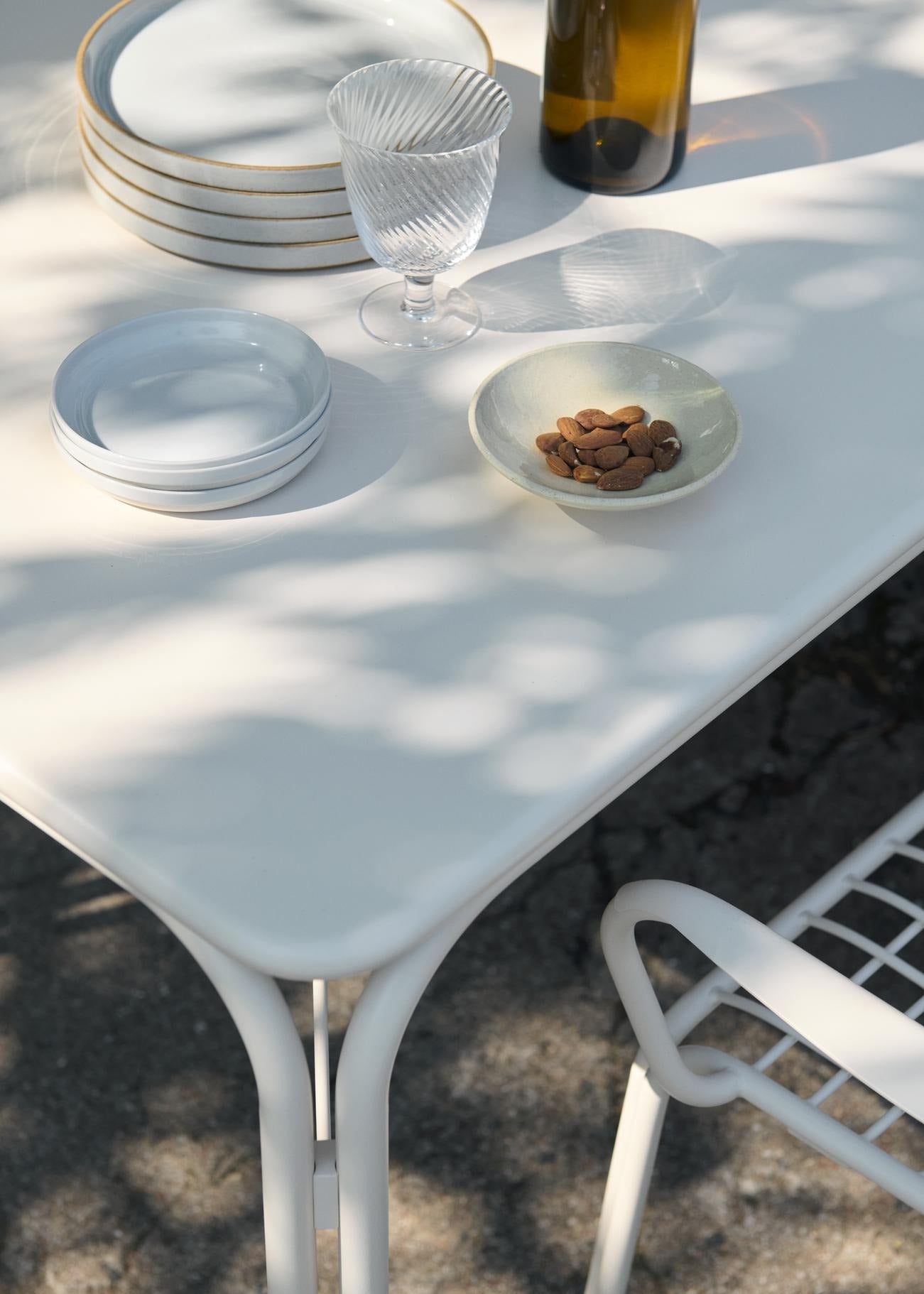 Mesa de comedor exterior &Tradition Thorvald SC99 en acero negro, diseño minimalista nórdico de Space Copenhagen para jardín; Thorvald Outdoor Dining Table SC99 — Thorvald Outdoor Dining Table SC99_Bronze Green_Angled Front; Thorvald Outdoor Dining Table SC99 — Thorvald Outdoor Dining Table SC99_Warm Black_Angled Front; Thorvald Outdoor Dining Table SC99 — ATD_Retail_2025_Thorvald SC99_Thorvald SC94_Momento Vase JH41; Thorvald Outdoor Dining Table SC99 — ATD_Retail_2025_Thorvald SC99_Collect SC79