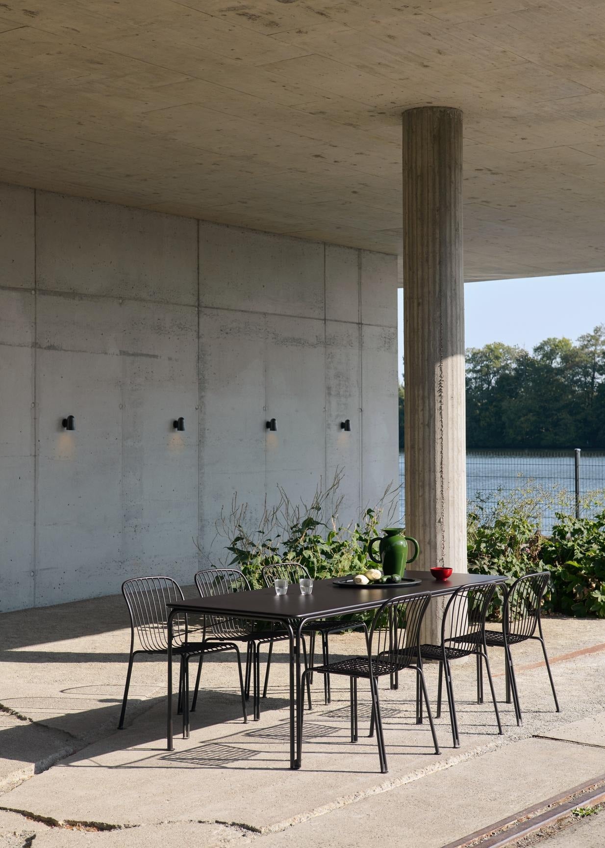 Mesa de comedor exterior &Tradition Thorvald SC99 en acero negro, diseño minimalista nórdico de Space Copenhagen para jardín; Thorvald Outdoor Dining Table SC99 — Thorvald Outdoor Dining Table SC99_Bronze Green_Angled Front; Thorvald Outdoor Dining Table SC99 — Thorvald Outdoor Dining Table SC99_Warm Black_Angled Front; Thorvald Outdoor Dining Table SC99 — ATD_Retail_2025_Thorvald SC99_Thorvald SC94_Momento Vase JH41; Thorvald Outdoor Dining Table SC99 — ATD_Retail_2025_Thorvald SC99_Collect SC79