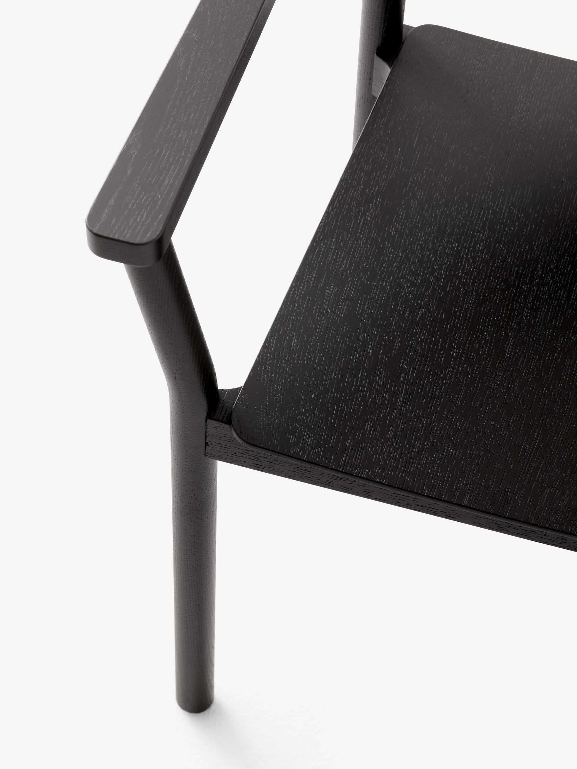Sillón Betty TK10 de &Tradition en madera maciza con respaldo curvado y brazos ergonómicos, diseño nórdico contemporáneo; Betty Armchair TK10 — Betty TK10_Smoked oak_angled front; Betty Armchair TK10 — Betty TK10_Clear lacquered oak_front angled; Betty Armchair TK10 — Betty TK10_Black_detail; Betty Armchair TK10 — ATD_Retail_2024_Betty TK10_Collect glass SC78