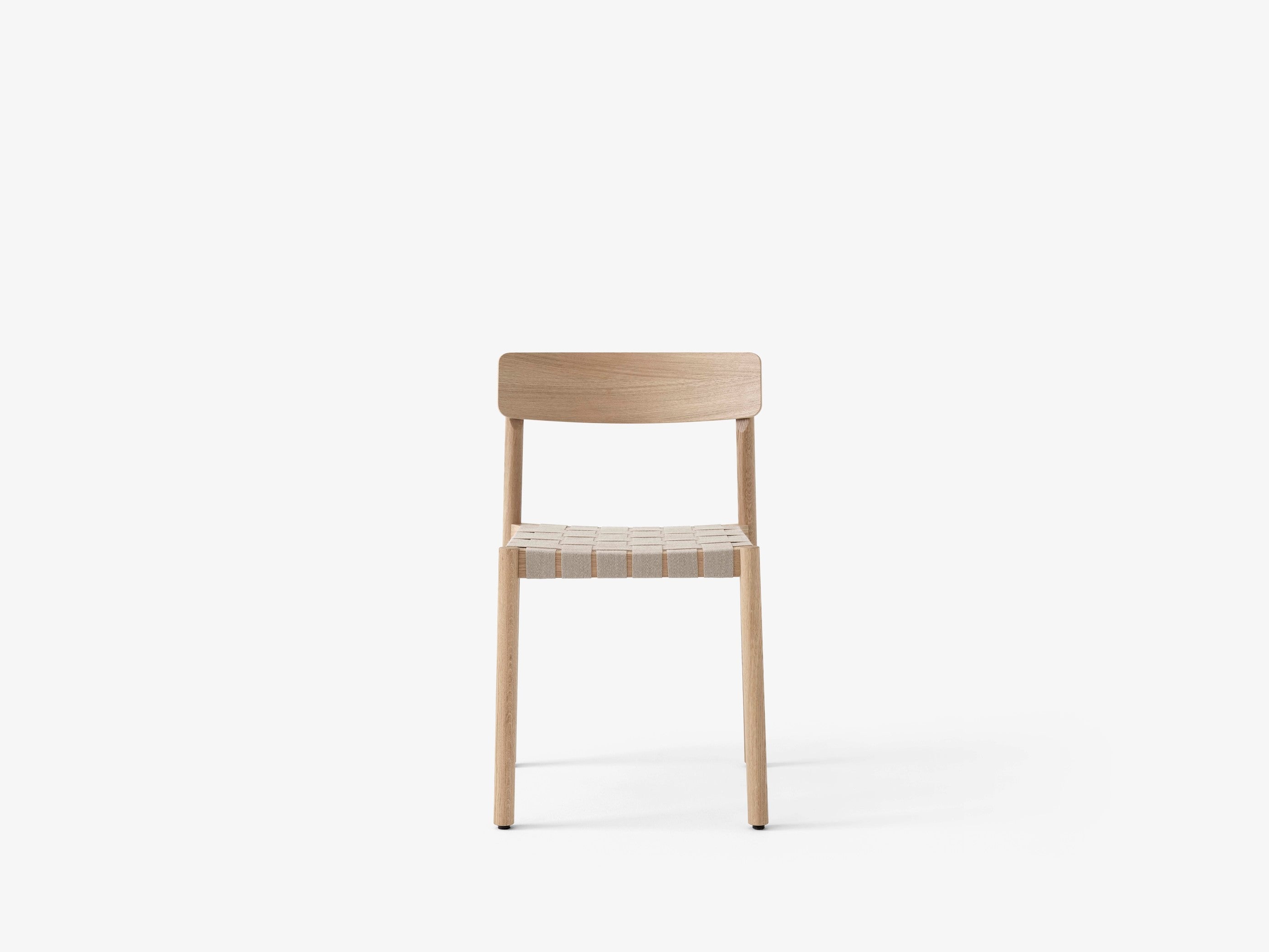 Silla de comedor Betty TK1 de &Tradition con estructura de madera maciza, respaldo de chapa y asiento con cinta de lino; Betty Side Chair TK1 — Betty TK1_Smoked oak w. natural webbing_angled front; Betty Side Chair TK1 — Betty TK1_Oak.front; Betty Side Chair TK1 — Betty TK1 Black w. linking system_rows_front; Betty Side Chair TK1 — ATD_Location_2019_Betty_TK1_InBetween_SK12