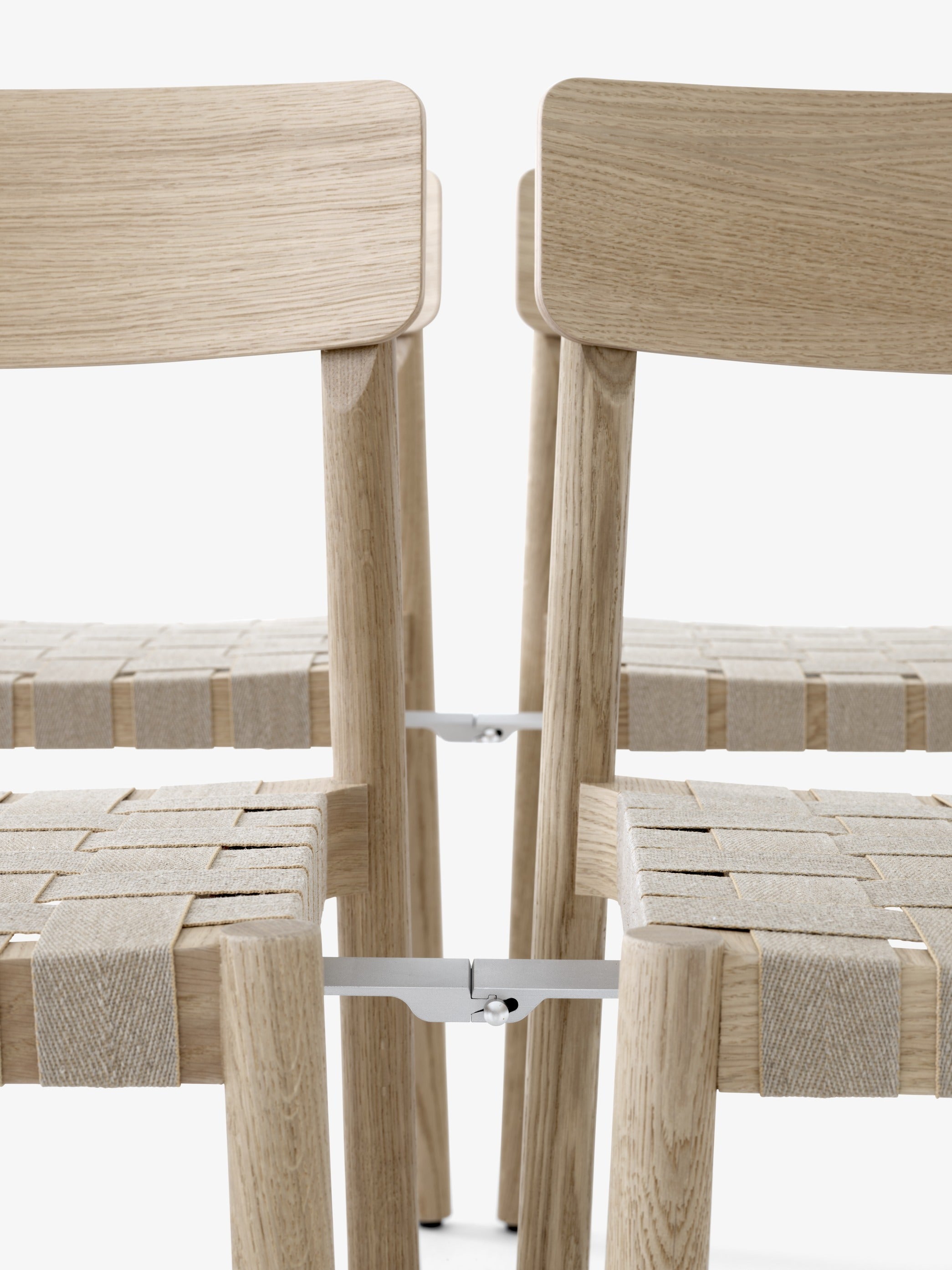 Silla de comedor Betty TK1 de &Tradition con estructura de madera maciza, respaldo de chapa y asiento con cinta de lino; Betty Side Chair TK1 — Betty TK1_Smoked oak w. natural webbing_angled front; Betty Side Chair TK1 — Betty TK1_Oak.front; Betty Side Chair TK1 — Betty TK1 Black w. linking system_rows_front; Betty Side Chair TK1 — ATD_Location_2019_Betty_TK1_InBetween_SK12