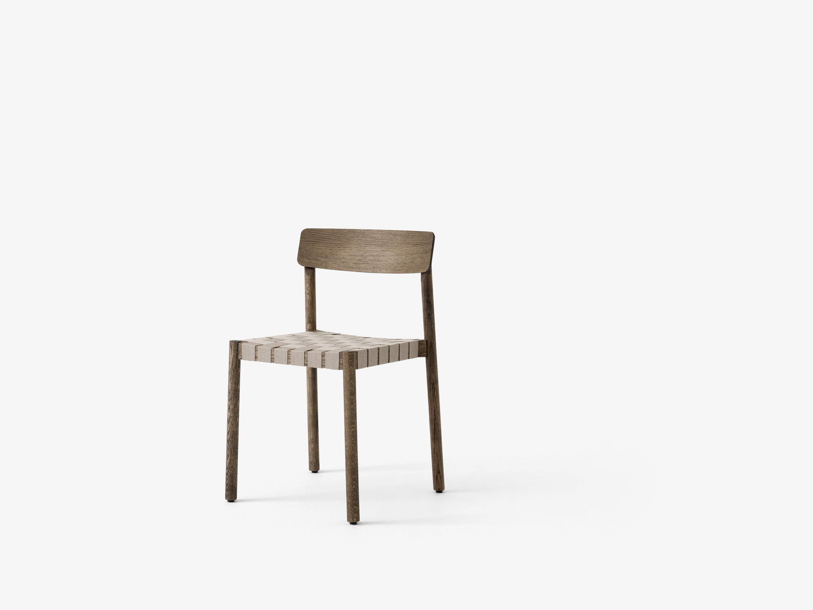 Silla de comedor Betty TK1 de &Tradition con estructura de madera maciza, respaldo de chapa y asiento con cinta de lino; Betty Side Chair TK1 — Betty TK1_Smoked oak w. natural webbing_angled front; Betty Side Chair TK1 — Betty TK1_Oak.front; Betty Side Chair TK1 — Betty TK1 Black w. linking system_rows_front; Betty Side Chair TK1 — ATD_Location_2019_Betty_TK1_InBetween_SK12
