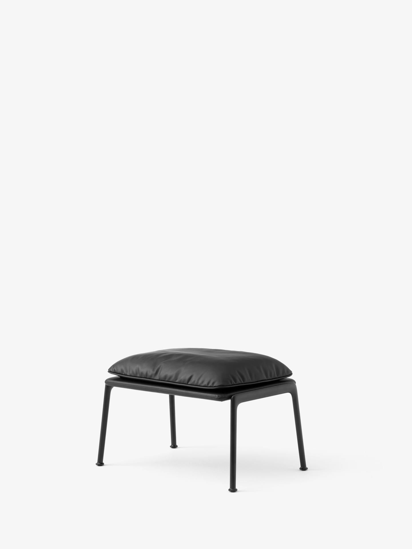 Reposapiés &Tradition Muno LN20 de Luca Nichetto con estructura de aluminio y tapizado contemporáneo sobre fondo neutro; Muno Footstool LN20 — Muno Footstool LN20_Warm Black Legs w. Clay 0007_Angled Front; Muno Footstool LN20 — Muno Footstool LN20_Warm Black Legs w. Cifrado 0221_Angled Front; Muno Footstool LN20 — Muno Footstool LN20_Warm Black Legs w. Noble Leather Black_Angled Front; Muno Footstool LN20 — Muno Footstool LN20_Warm Black Legs w. Ecriture 0780_Angled Front