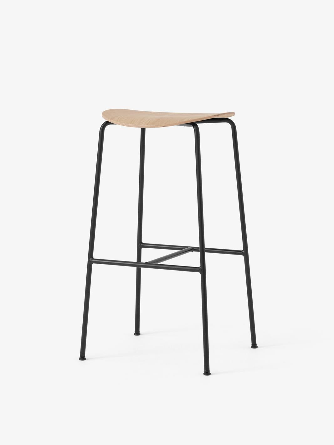 Taburete de bar &Tradition Pavilion AV38 con estructura de tubos de acero y asiento de chapa moldeada diseñado por Anderssen ; Pavilion Bar Stool AV38 — Pavilion Bar Stool AV38_Black frame_Black Lacquered Oak_Angled Front; Pavilion Bar Stool AV38 — Pavilion Bar Stool AV38_Black frame_Lacquered Oak_Angled Front