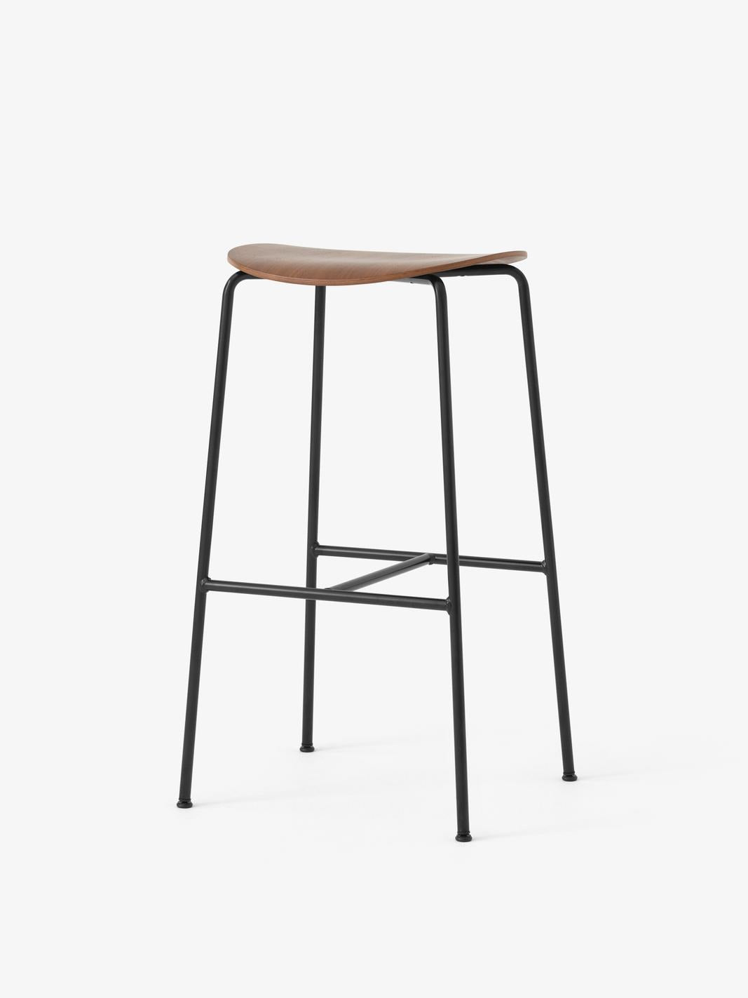 Taburete de bar &Tradition Pavilion AV38 con estructura de tubos de acero y asiento de chapa moldeada diseñado por Anderssen ; Pavilion Bar Stool AV38 — Pavilion Bar Stool AV38_Black frame_Black Lacquered Oak_Angled Front; Pavilion Bar Stool AV38 — Pavilion Bar Stool AV38_Black frame_Lacquered Oak_Angled Front
